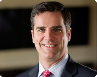 Headshot of Peter Long wearing a black suit with a red tie.