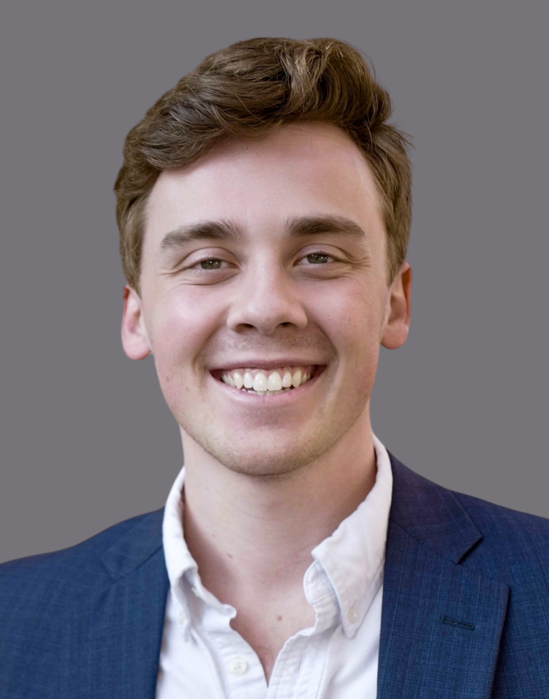 A smiling young man in a suit and white shirt.