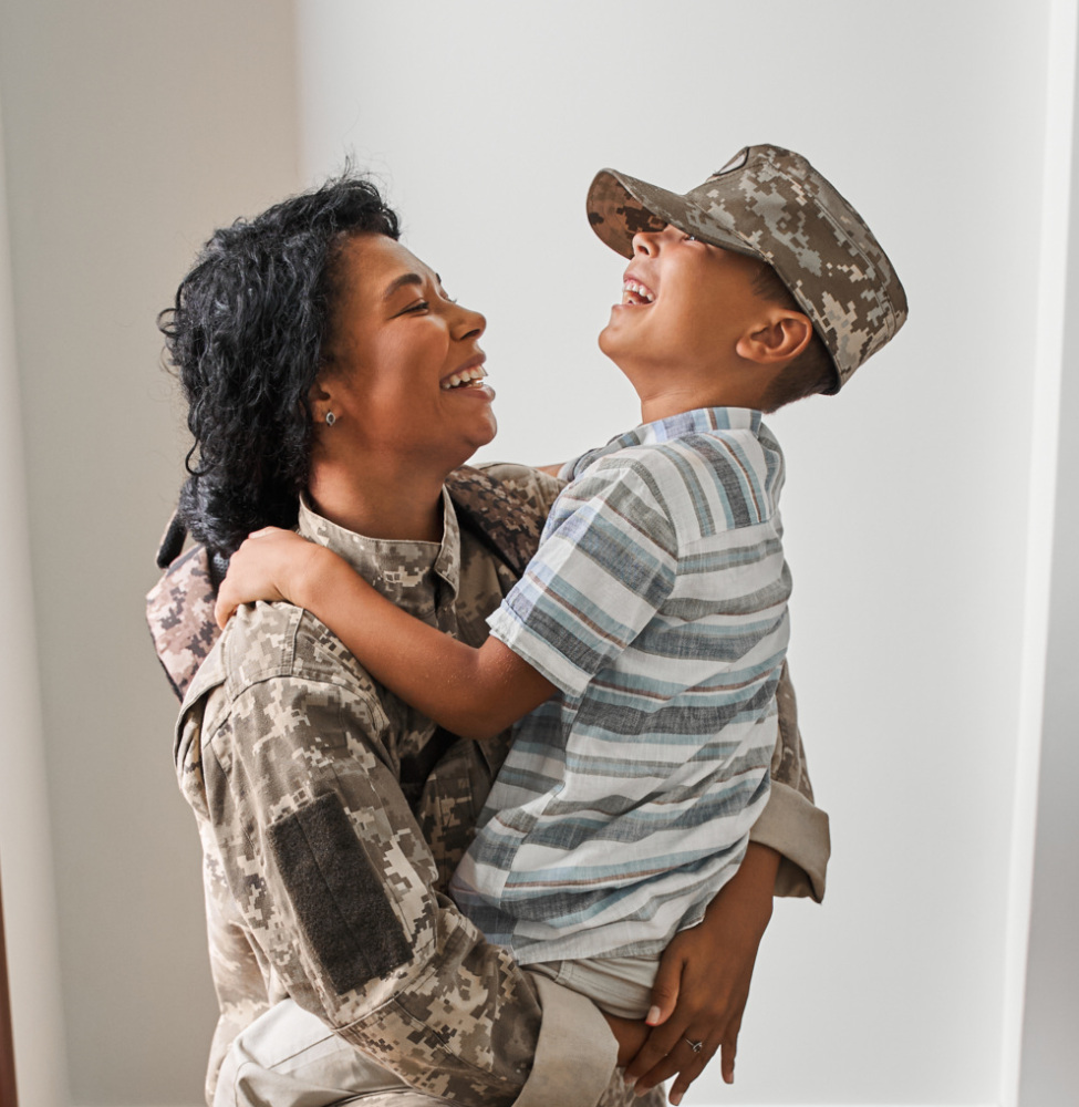 A woman in a military uniform is hugging her son.