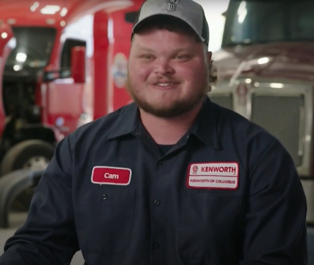 Cam, an ADTC participant, smiles at the camera in his gray jumpsuit uniform.