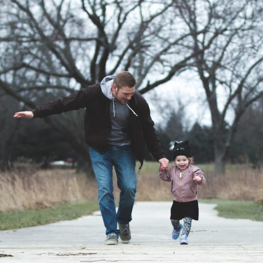 Man and his young daughter running in a park.