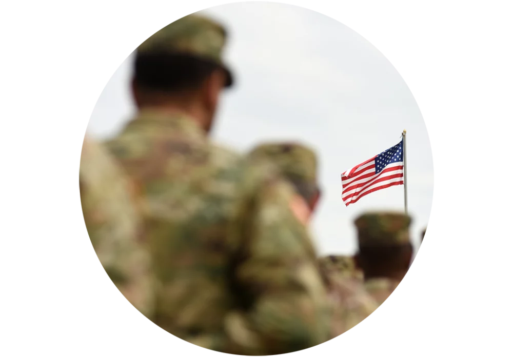 Uniformed military personnel walk with a small American flag