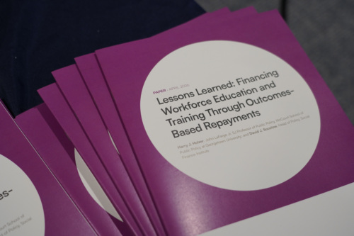 A stack of purple-covered reports titled "Lessons Learned: Financing Workforce Education and Training Through Outcomes-Based Repayments.